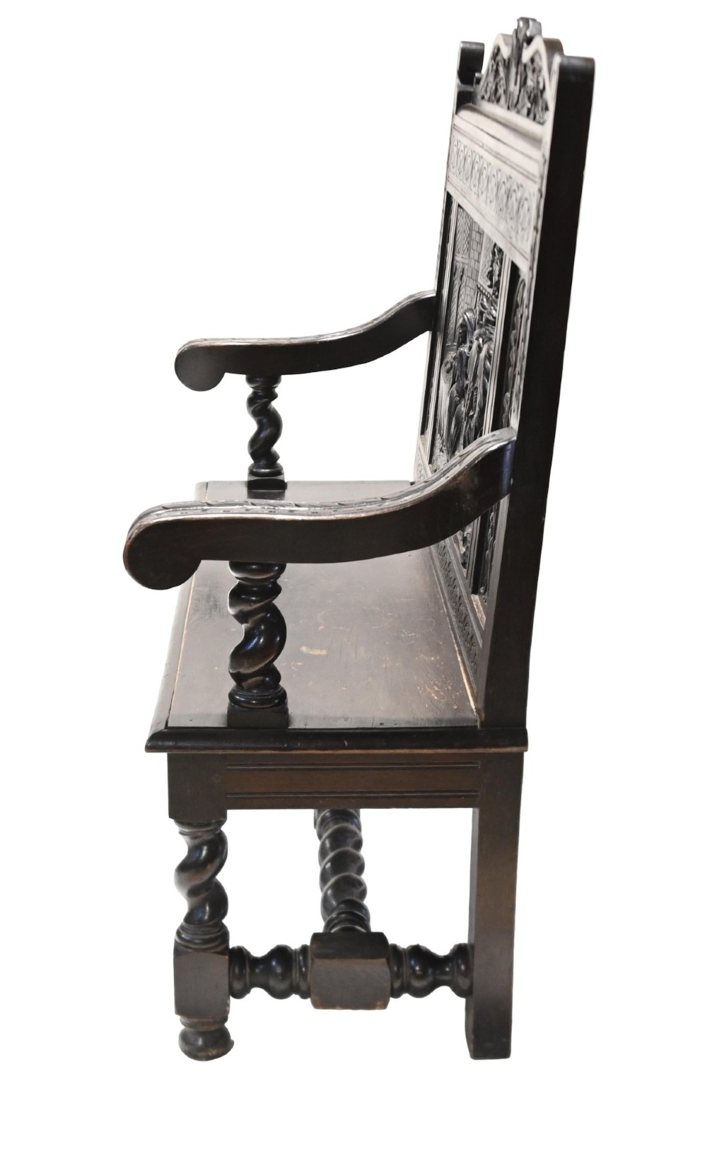 A late 19th-century dark carved walnut hall bench featuring a pictorial relief back panel, scrolled armrests, and turned stretchers. View XI