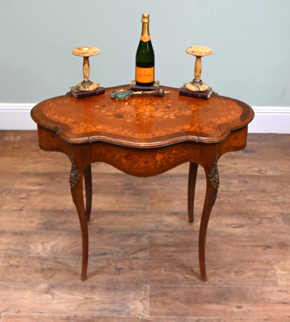 A shaped French Louis XV style writing table crafted from warm brown wood featuring intricate floral marquetry inlay, cabriole legs, and bronze mounts. View II