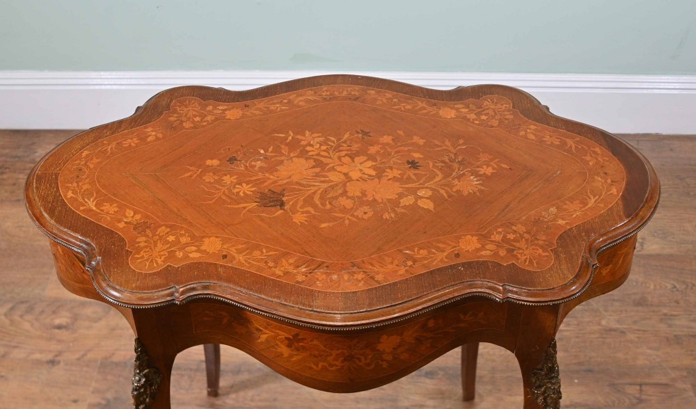 A shaped French Louis XV style writing table crafted from warm brown wood featuring intricate floral marquetry inlay, cabriole legs, and bronze mounts. View III