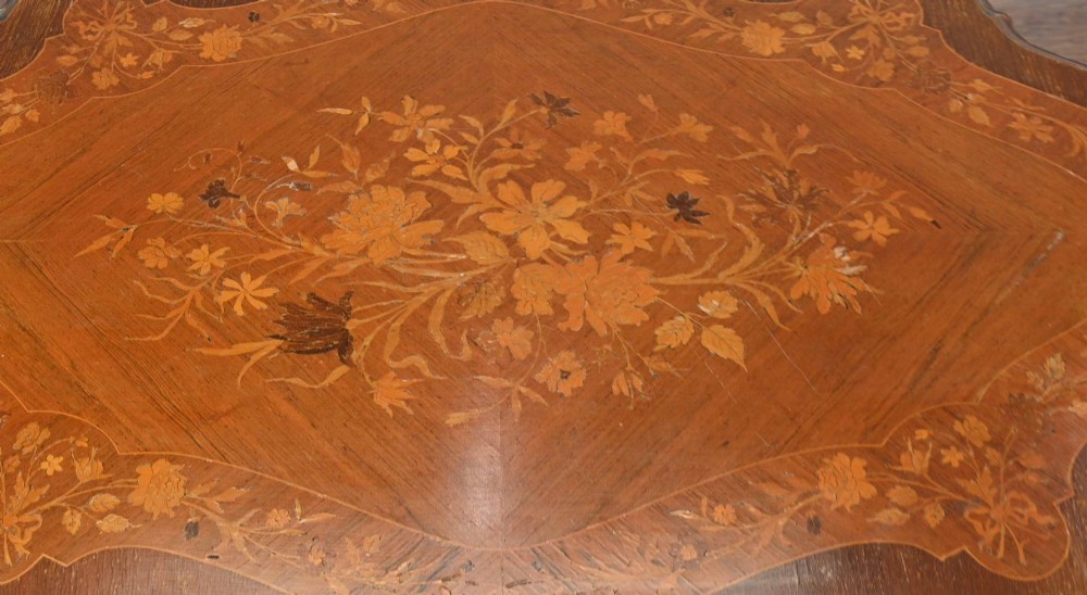 A shaped French Louis XV style writing table crafted from warm brown wood featuring intricate floral marquetry inlay, cabriole legs, and bronze mounts. View IV