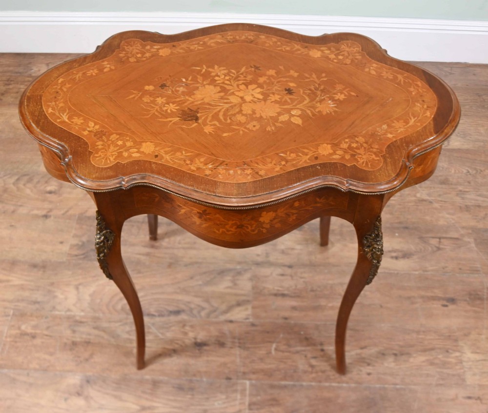A shaped French Louis XV style writing table crafted from warm brown wood featuring intricate floral marquetry inlay, cabriole legs, and bronze mounts. View VI