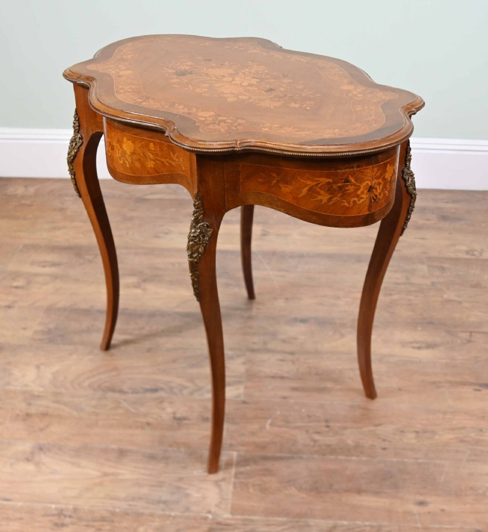 A shaped French Louis XV style writing table crafted from warm brown wood featuring intricate floral marquetry inlay, cabriole legs, and bronze mounts. View VII
