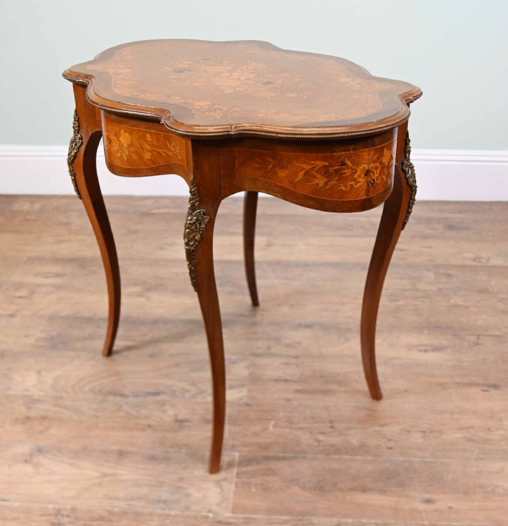 A shaped French Louis XV style writing table crafted from warm brown wood featuring intricate floral marquetry inlay, cabriole legs, and bronze mounts. View VIII