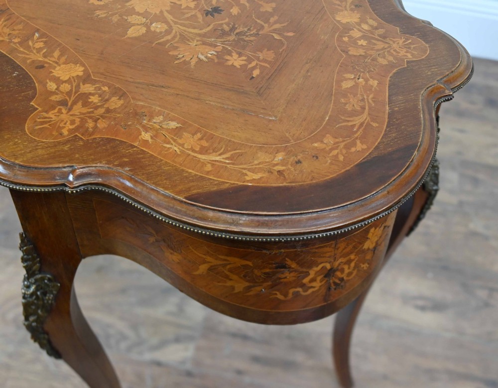 A shaped French Louis XV style writing table crafted from warm brown wood featuring intricate floral marquetry inlay, cabriole legs, and bronze mounts. View IX