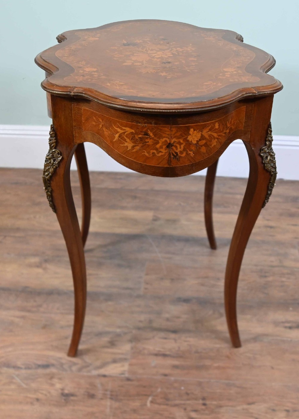 A shaped French Louis XV style writing table crafted from warm brown wood featuring intricate floral marquetry inlay, cabriole legs, and bronze mounts. View X