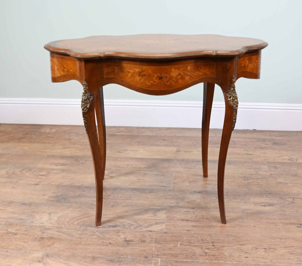 A shaped French Louis XV style writing table crafted from warm brown wood featuring intricate floral marquetry inlay, cabriole legs, and bronze mounts. View XI