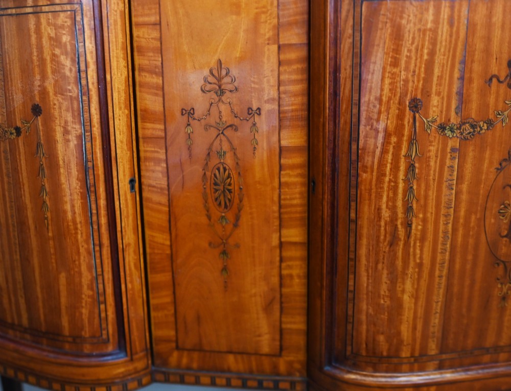 An Edwardian Sheraton Revival display cabinet in painted satinwood with glazed double doors, decorative oval glazing bars, and lower cupboard doors on slender square legs. View VI