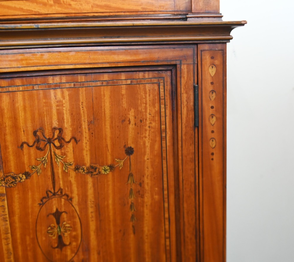 An Edwardian Sheraton Revival display cabinet in painted satinwood with glazed double doors, decorative oval glazing bars, and lower cupboard doors on slender square legs. View VII