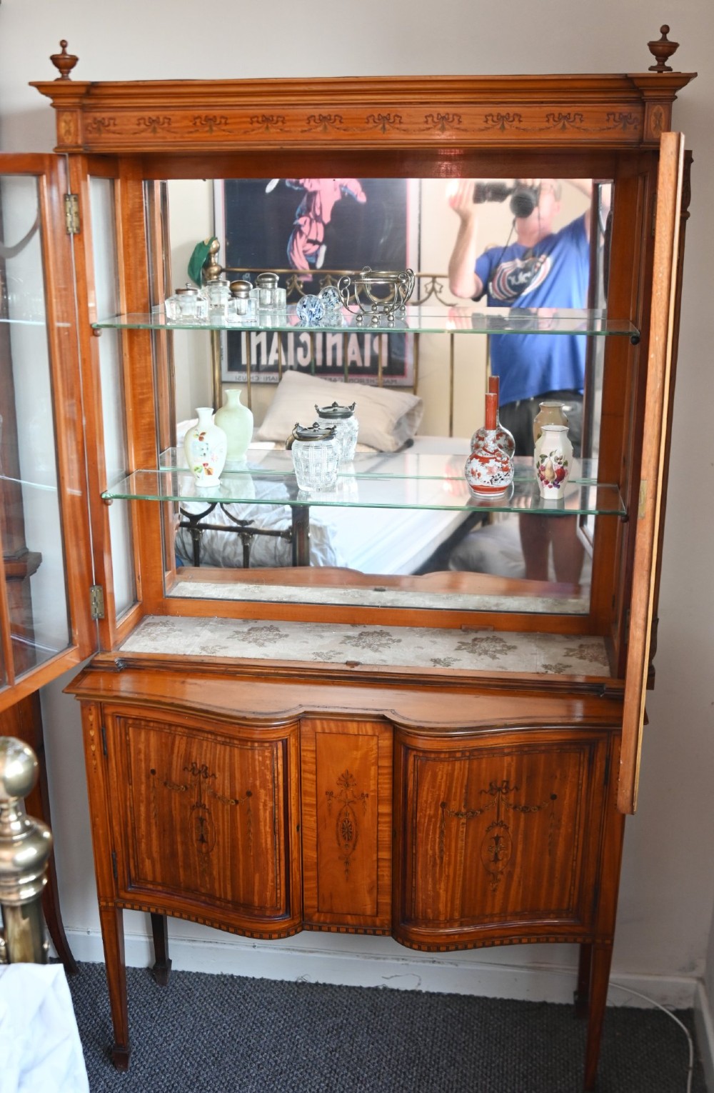 An Edwardian Sheraton Revival display cabinet in painted satinwood with glazed double doors, decorative oval glazing bars, and lower cupboard doors on slender square legs. View IX