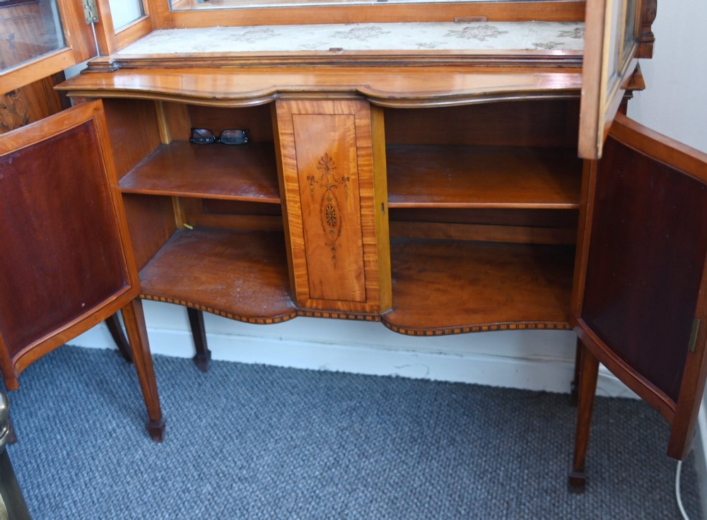 An Edwardian Sheraton Revival display cabinet in painted satinwood with glazed double doors, decorative oval glazing bars, and lower cupboard doors on slender square legs. View XI