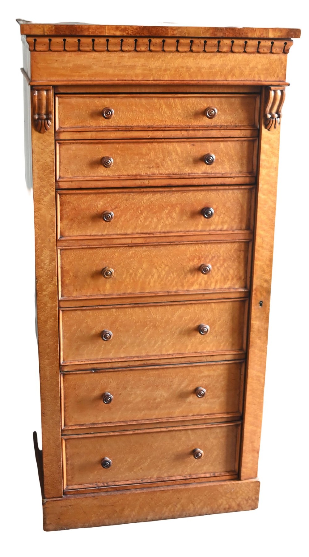 A tall Victorian birds eye maple Wellington chest featuring seven drawers with turned wooden knobs and a side locking flap.