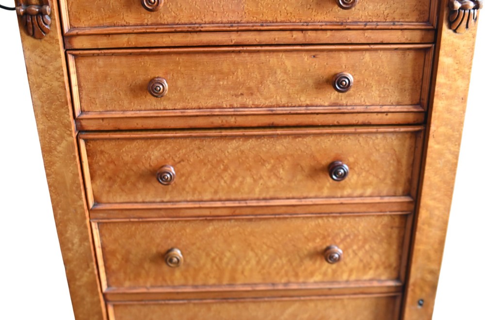 A tall Victorian birds eye maple Wellington chest featuring seven drawers with turned wooden knobs and a side locking flap. View III