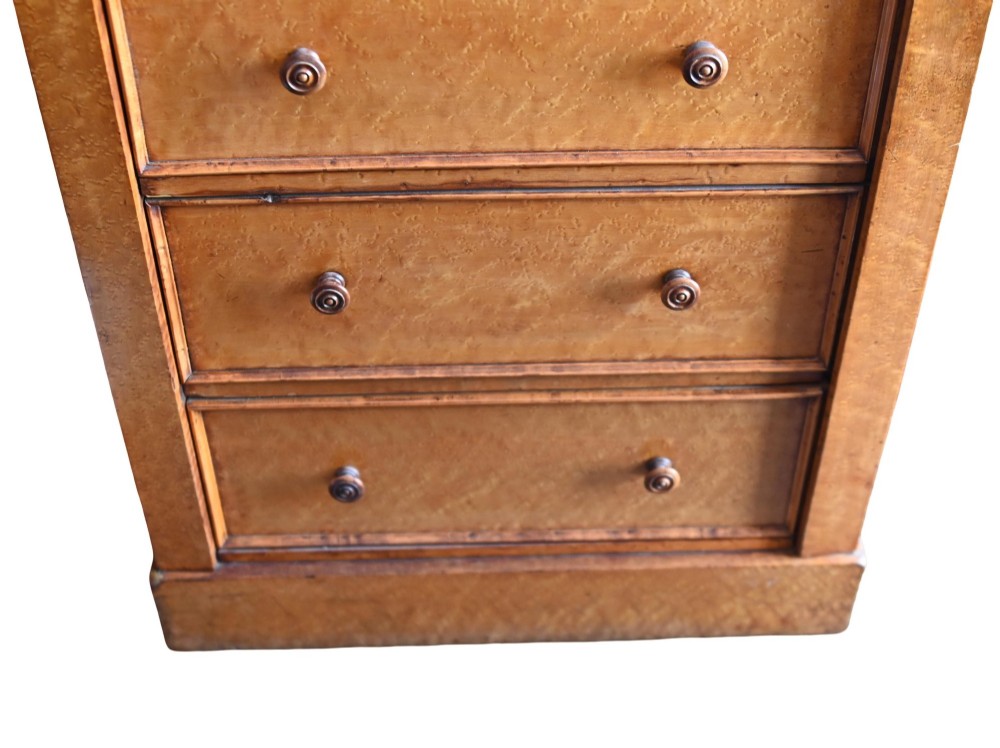 A tall Victorian birds eye maple Wellington chest featuring seven drawers with turned wooden knobs and a side locking flap. View IV