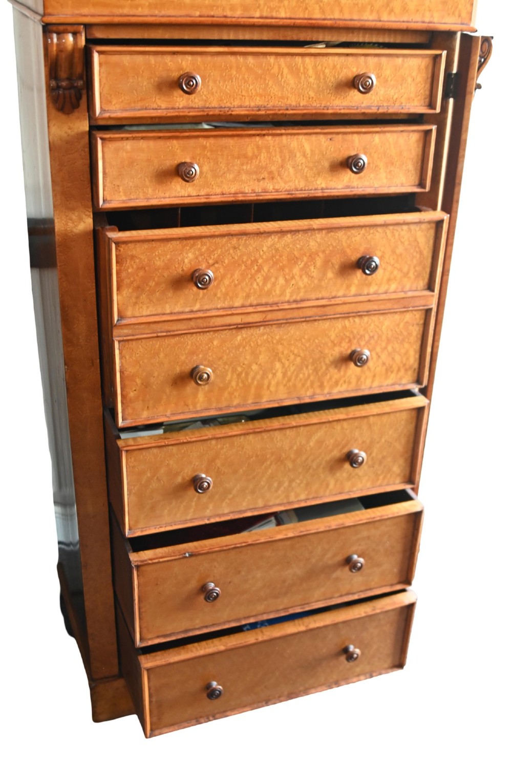 A tall Victorian birds eye maple Wellington chest featuring seven drawers with turned wooden knobs and a side locking flap. View VII