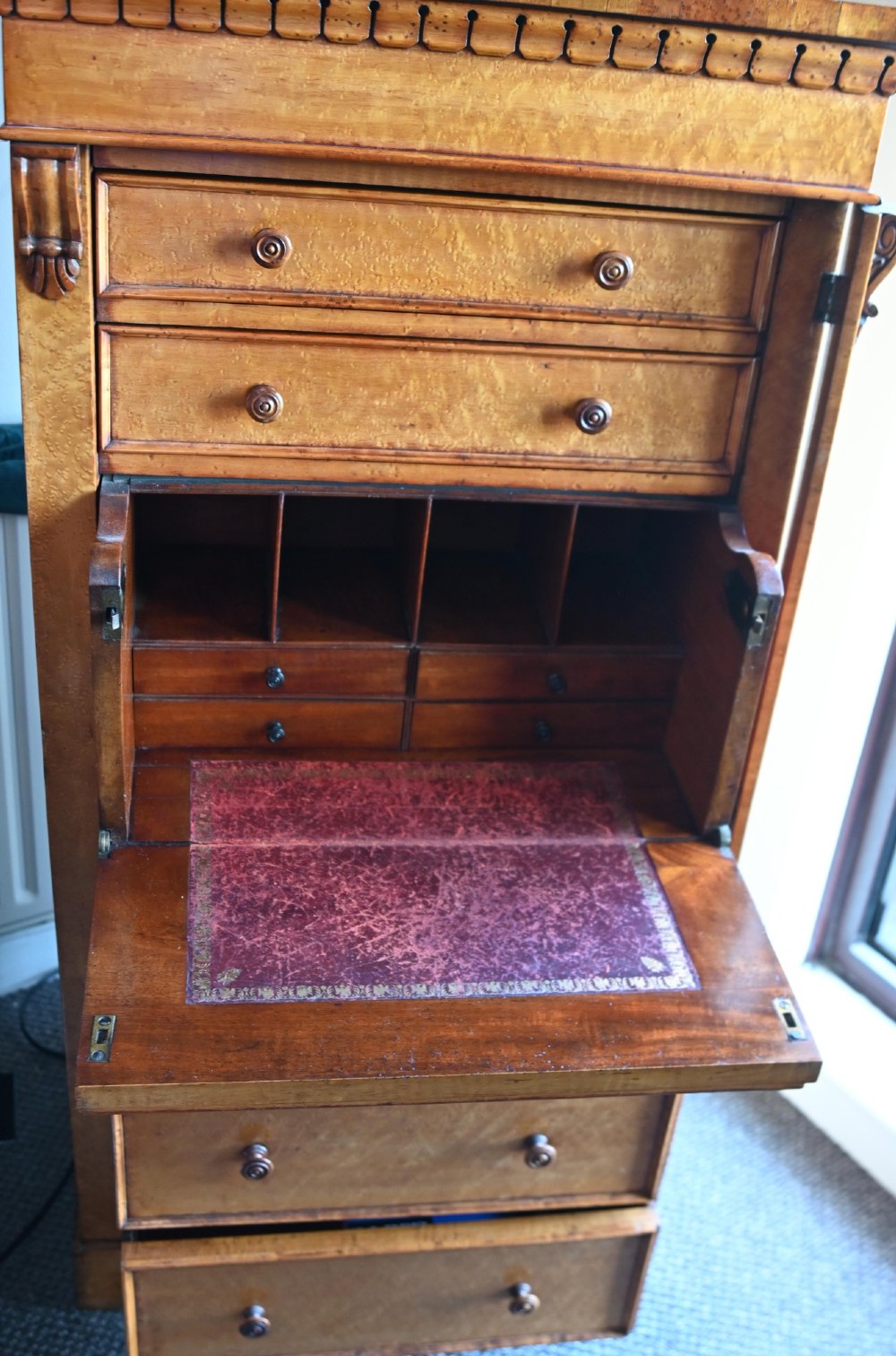 A tall Victorian birds eye maple Wellington chest featuring seven drawers with turned wooden knobs and a side locking flap. View X