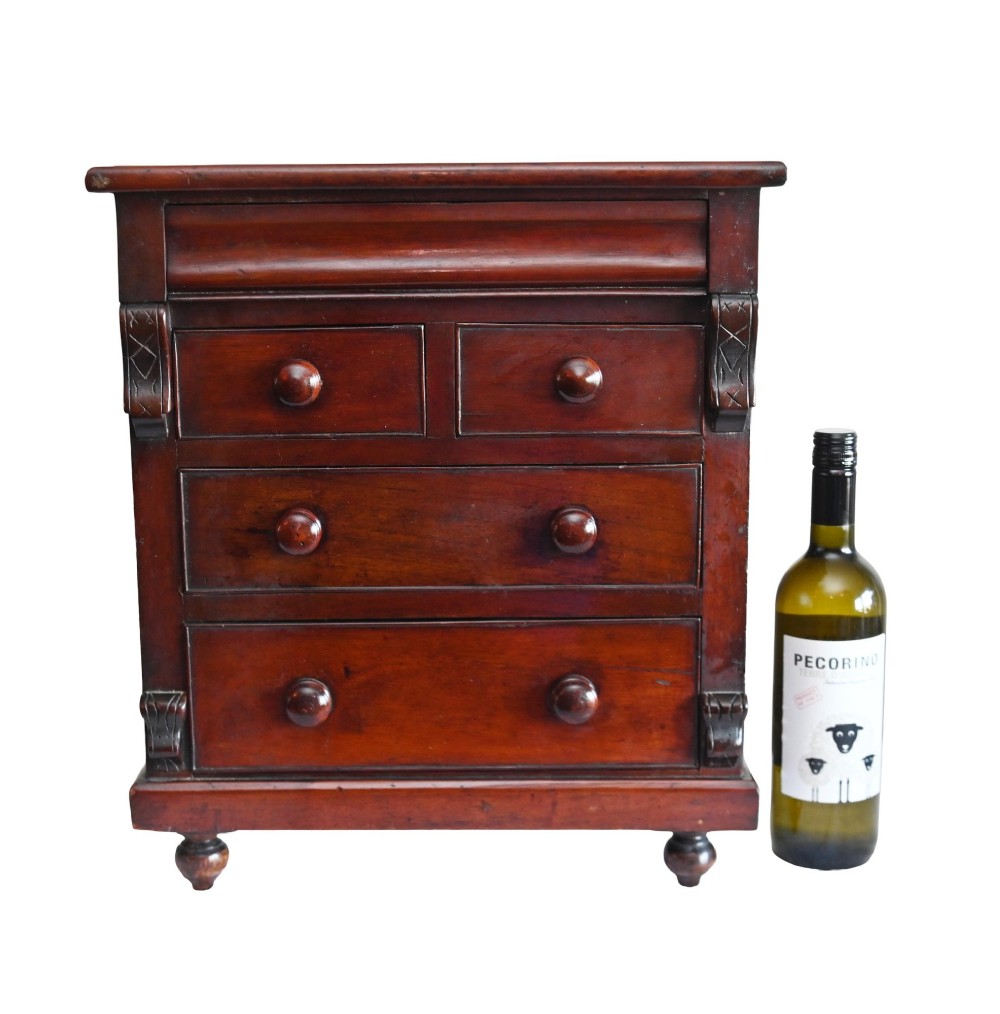 A 19th-century Scottish mahogany miniature apprentice chest featuring two short over two long drawers, a top cushion drawer, turned knobs, carved corbels, and turned feet. View II