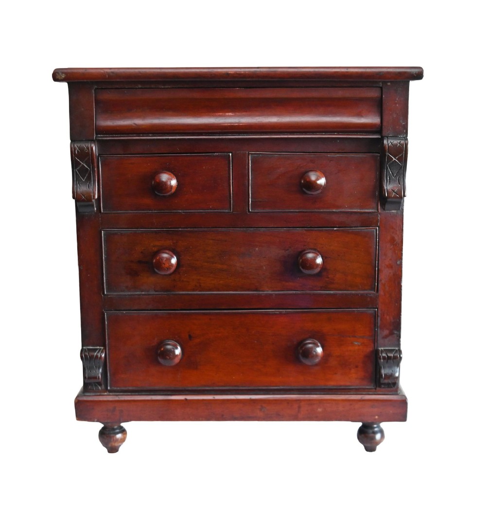 A 19th-century Scottish mahogany miniature apprentice chest featuring two short over two long drawers, a top cushion drawer, turned knobs, carved corbels, and turned feet.