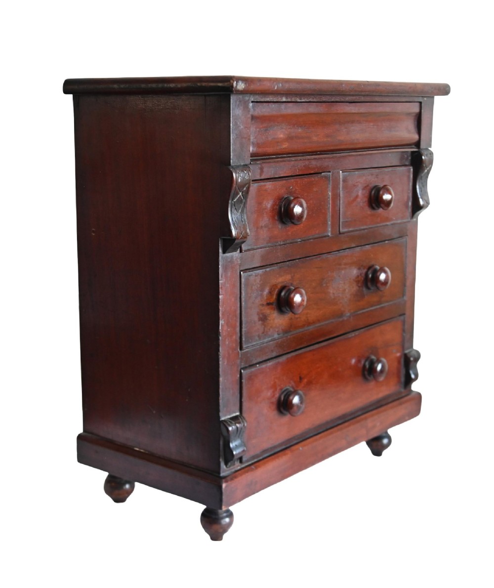 A 19th-century Scottish mahogany miniature apprentice chest featuring two short over two long drawers, a top cushion drawer, turned knobs, carved corbels, and turned feet. View IV