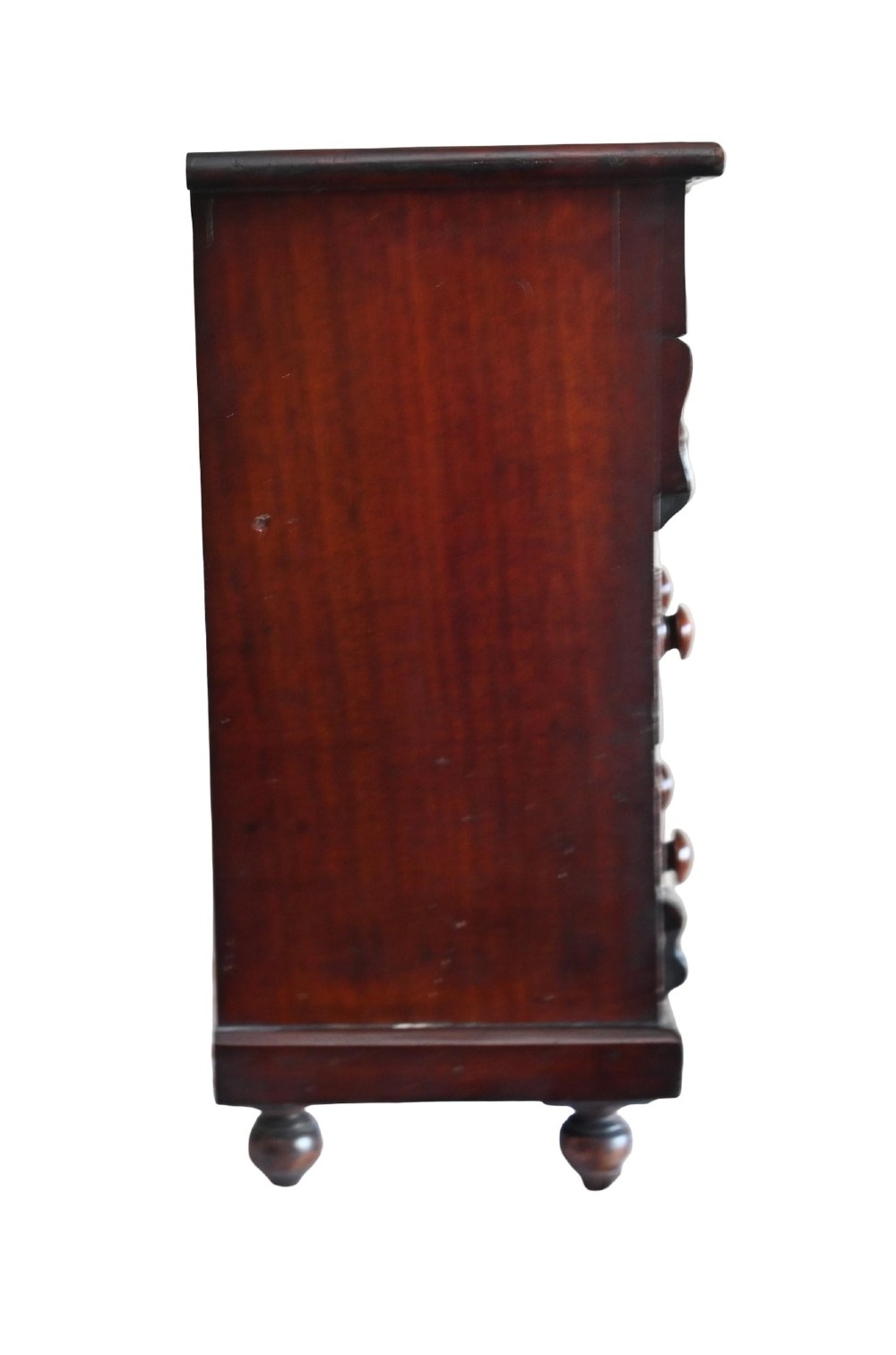 A 19th-century Scottish mahogany miniature apprentice chest featuring two short over two long drawers, a top cushion drawer, turned knobs, carved corbels, and turned feet. View VI