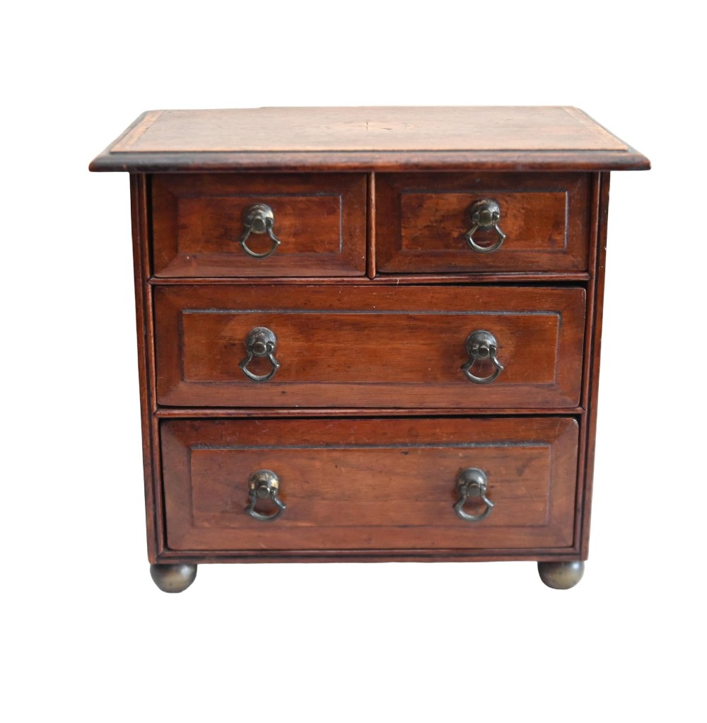 A Georgian Revival mahogany apprentice chest featuring two small top drawers over two full-width drawers with brass drop handles and an inlaid top border.