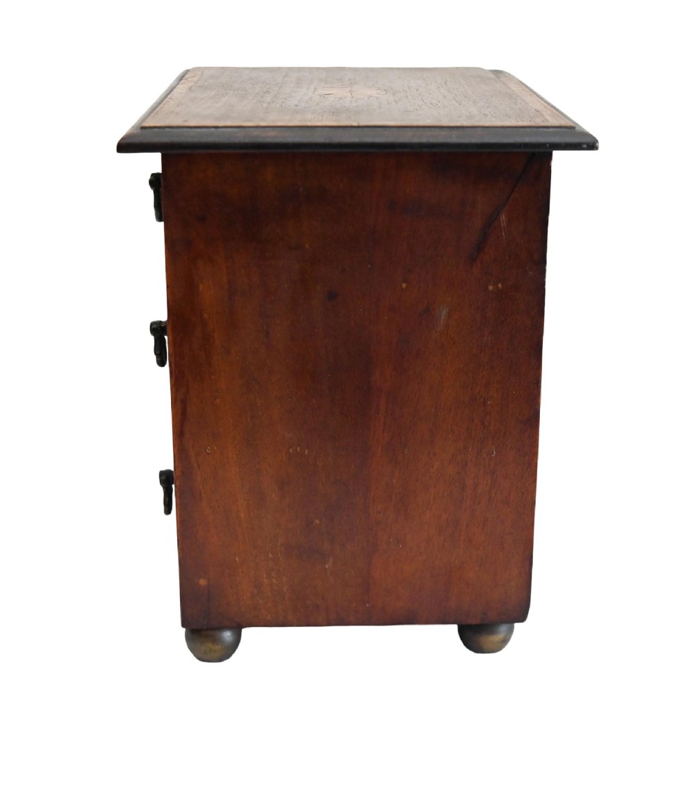 A Georgian Revival mahogany apprentice chest featuring two small top drawers over two full-width drawers with brass drop handles and an inlaid top border. View VI