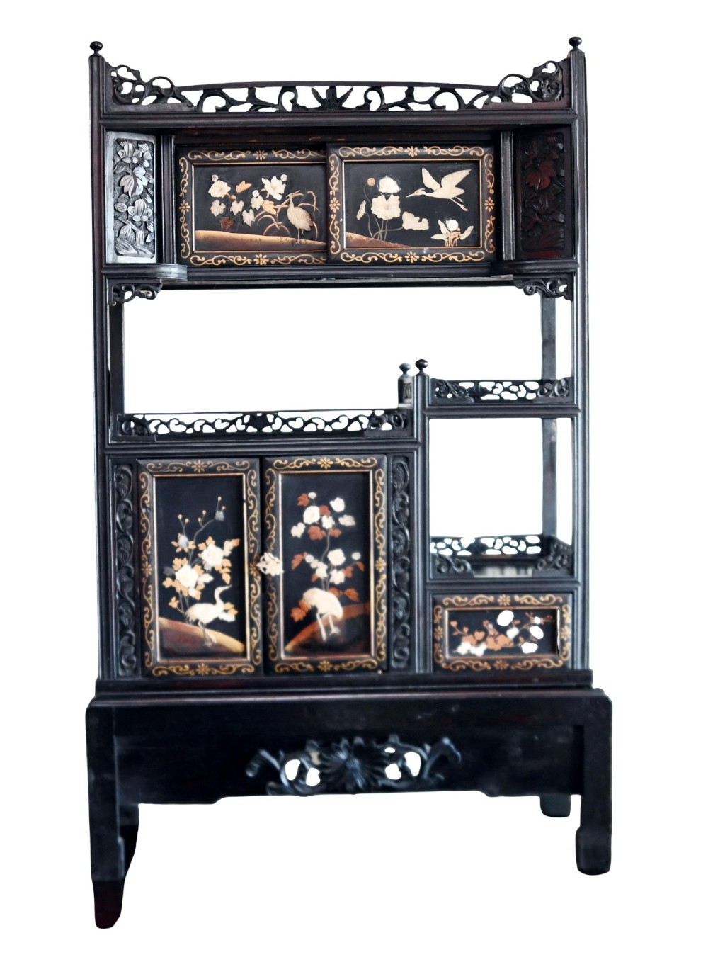 An antique ebonised Chinese display cabinet featuring asymmetrical shelves, pierced fretwork, and panels decorated with mother-of-pearl crane and botanical inlays.
