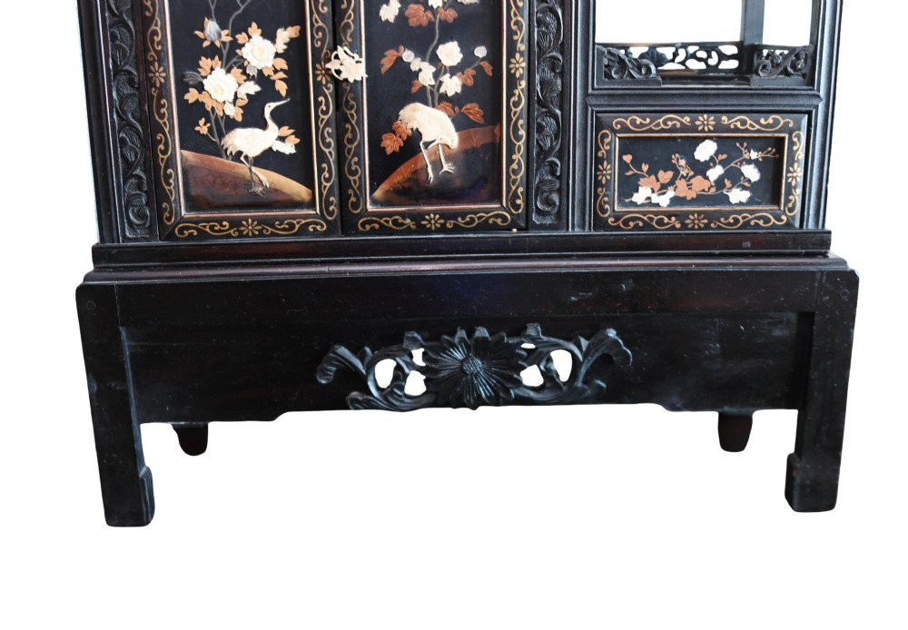 An antique ebonised Chinese display cabinet featuring asymmetrical shelves, pierced fretwork, and panels decorated with mother-of-pearl crane and botanical inlays. View III