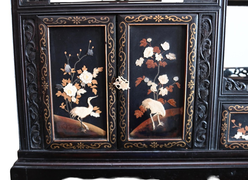 An antique ebonised Chinese display cabinet featuring asymmetrical shelves, pierced fretwork, and panels decorated with mother-of-pearl crane and botanical inlays. View V