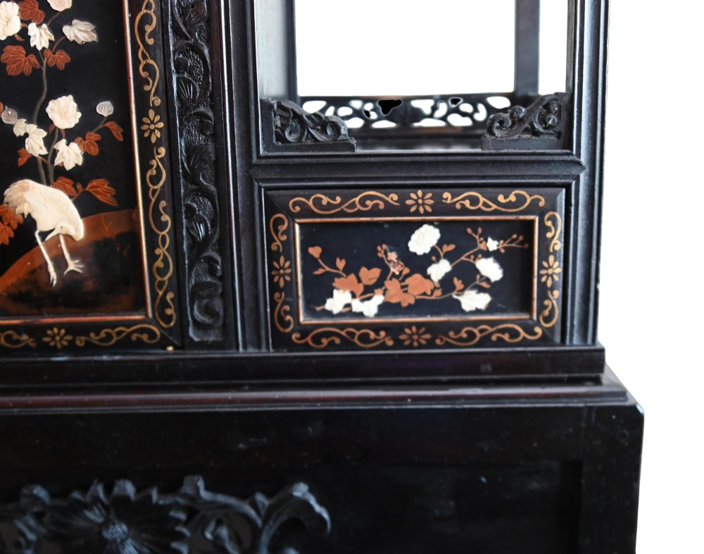 An antique ebonised Chinese display cabinet featuring asymmetrical shelves, pierced fretwork, and panels decorated with mother-of-pearl crane and botanical inlays. View VI