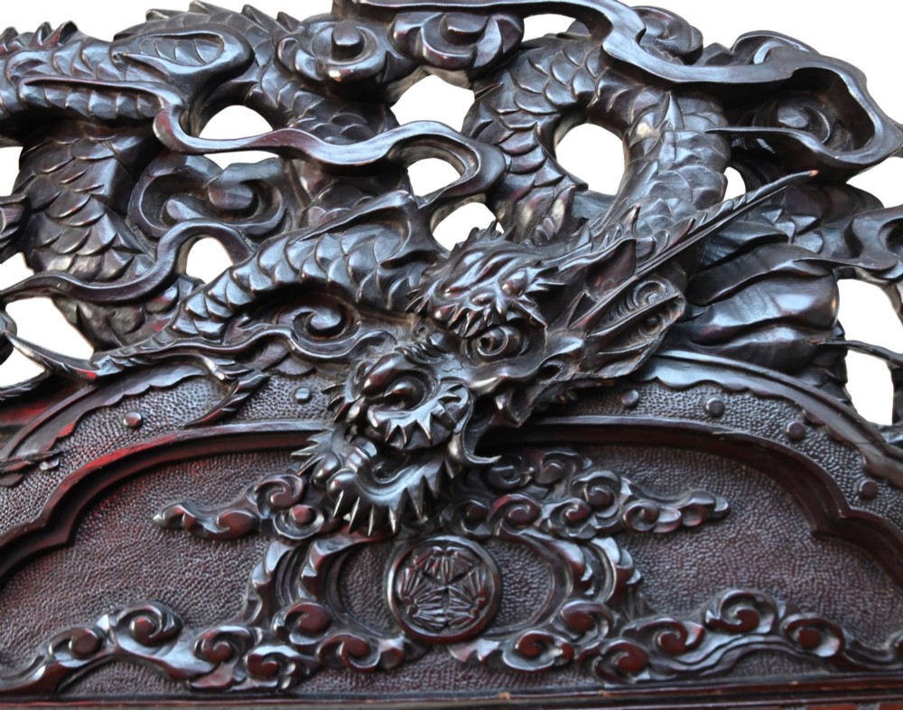 An intricately carved dark hardwood Japanese Meiji display cabinet featuring a dragon pediment, glazed door, and tiered asymmetrical shelves. View III