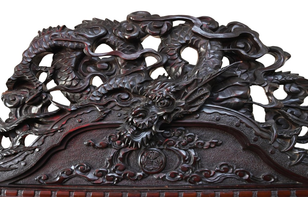 An intricately carved dark hardwood Japanese Meiji display cabinet featuring a dragon pediment, glazed door, and tiered asymmetrical shelves. View V