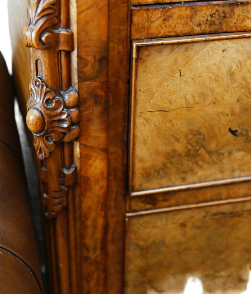 A tall 19th-century French Louis Philippe secretaire desk featuring figured birds-eye maple veneer, carved wooden handles, upper cabinet doors, and finials on top. View VI