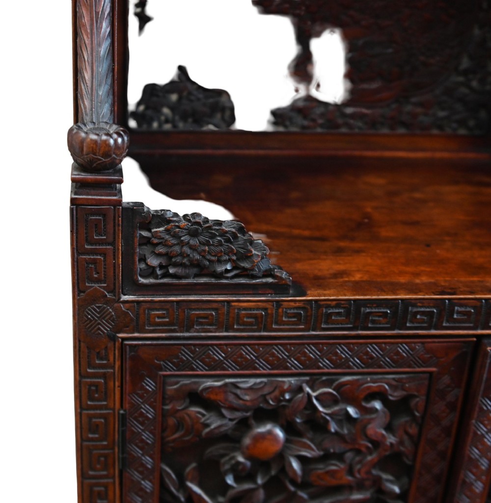 An intricately carved dark brown Japanese Meiji period display cabinet featuring asymmetrical open shelves, relief-carved cupboard doors, and a decorative cresting piece. View XIII