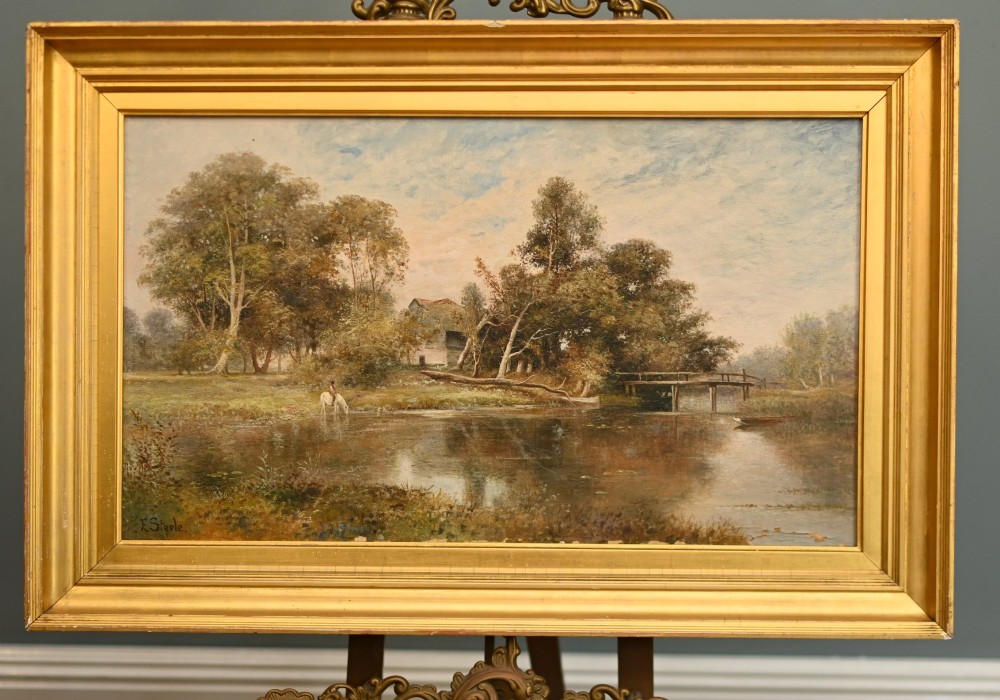 A 19th-century Victorian oil painting depicting a river landscape with trees and a wooden bridge, housed in a moulded gold gilt frame. View II