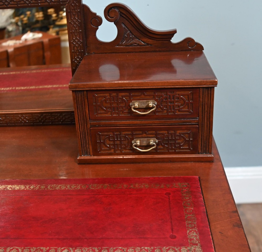 A mahogany ladies writing desk featuring a red leather inset writing surface, a central mirror superstructure flanked by drawers, and turned legs on castors. View II