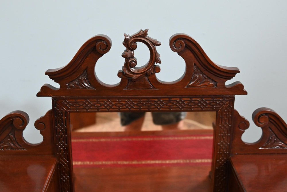 A mahogany ladies writing desk featuring a red leather inset writing surface, a central mirror superstructure flanked by drawers, and turned legs on castors. View III