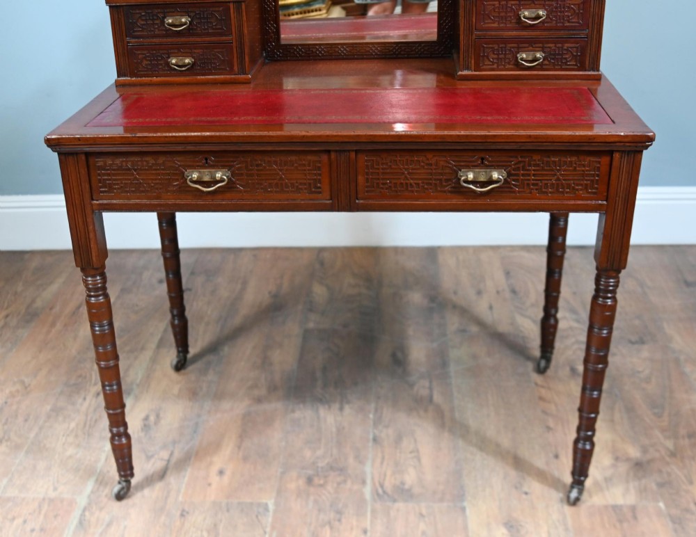 A mahogany ladies writing desk featuring a red leather inset writing surface, a central mirror superstructure flanked by drawers, and turned legs on castors. View V