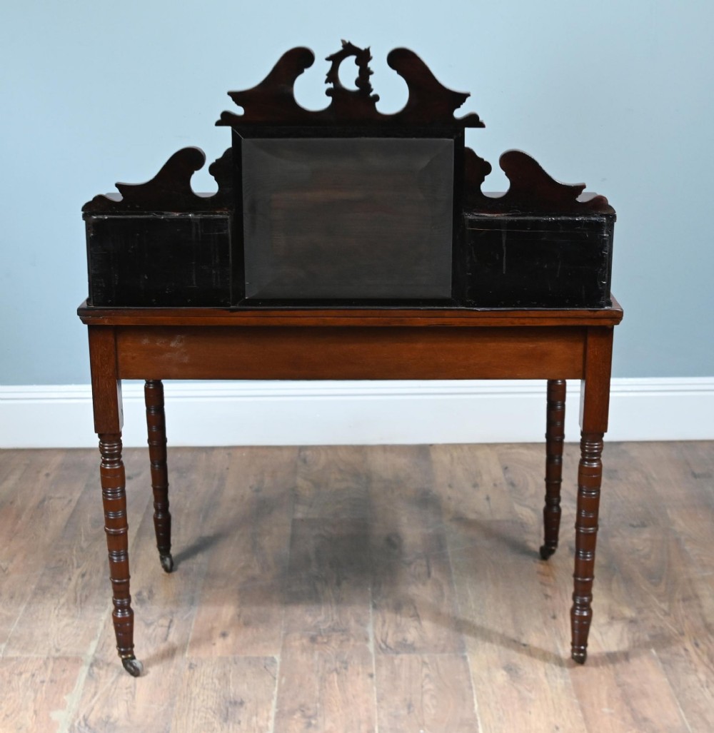 A mahogany ladies writing desk featuring a red leather inset writing surface, a central mirror superstructure flanked by drawers, and turned legs on castors. View IX