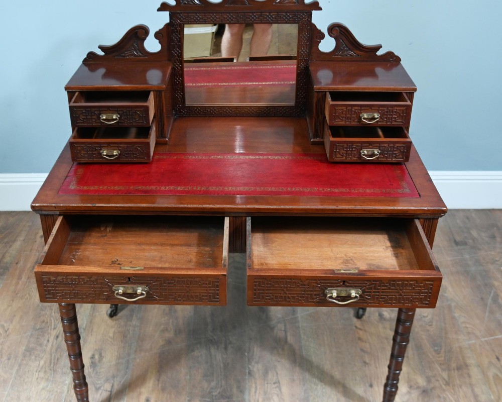 A mahogany ladies writing desk featuring a red leather inset writing surface, a central mirror superstructure flanked by drawers, and turned legs on castors. View X