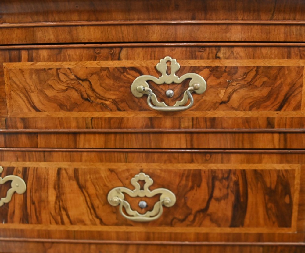 An 18th-century George II walnut chest on chest featuring figured veneered drawer fronts, brass swan-neck handles, and bracket feet. View IV