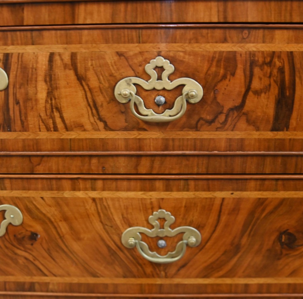 An 18th-century George II walnut chest on chest featuring figured veneered drawer fronts, brass swan-neck handles, and bracket feet. View V