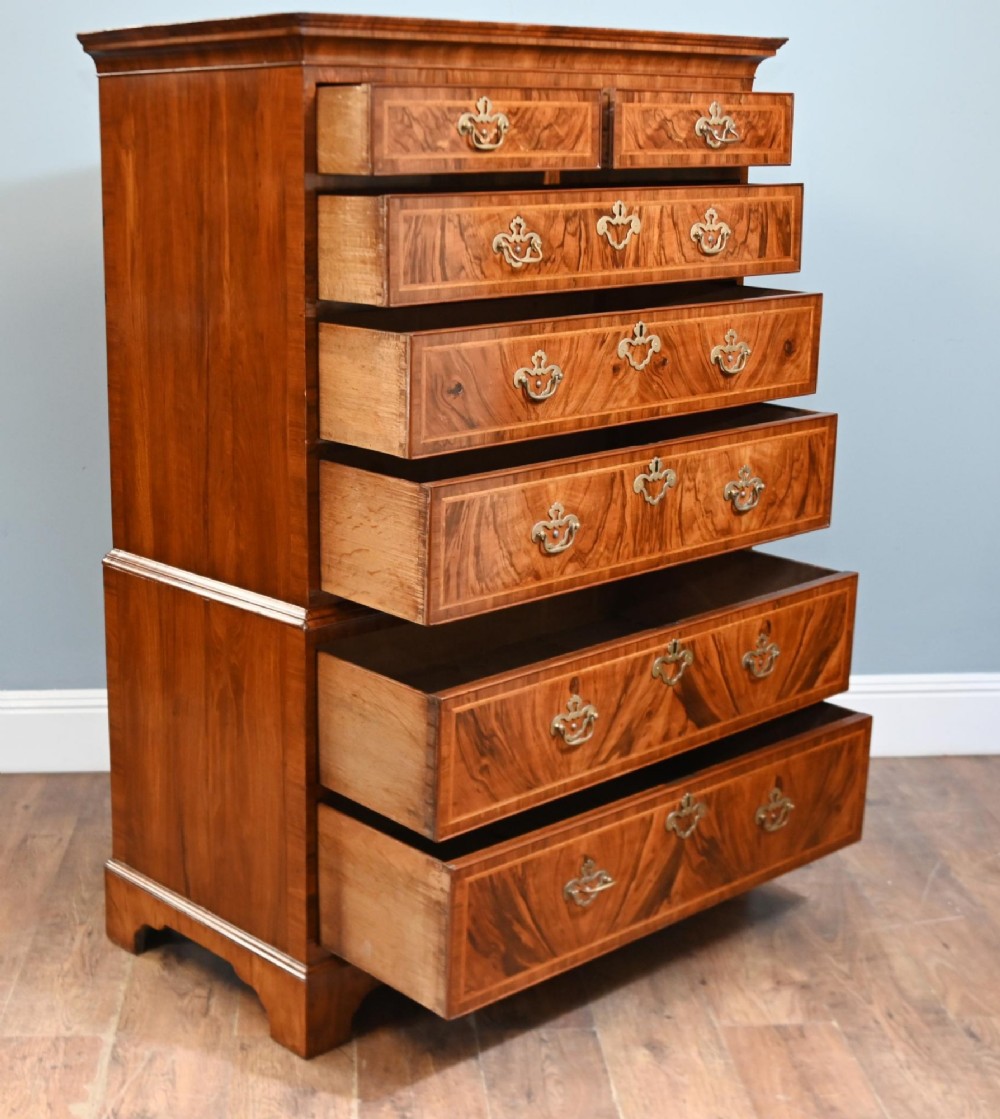 An 18th-century George II walnut chest on chest featuring figured veneered drawer fronts, brass swan-neck handles, and bracket feet. View VI