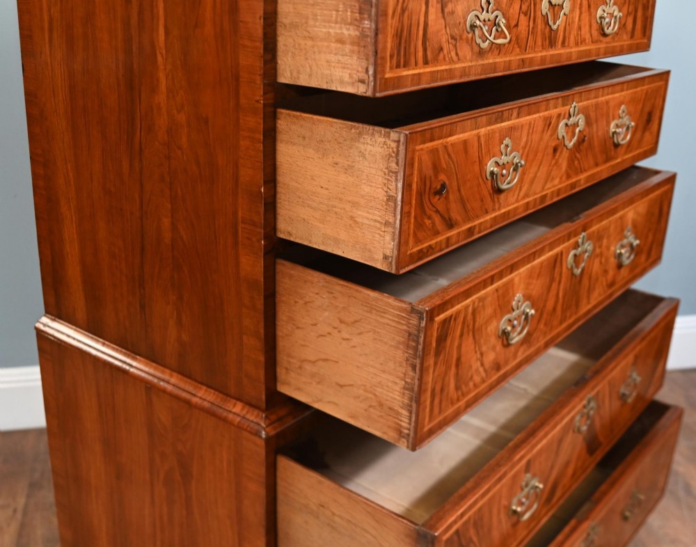 An 18th-century George II walnut chest on chest featuring figured veneered drawer fronts, brass swan-neck handles, and bracket feet. View VII