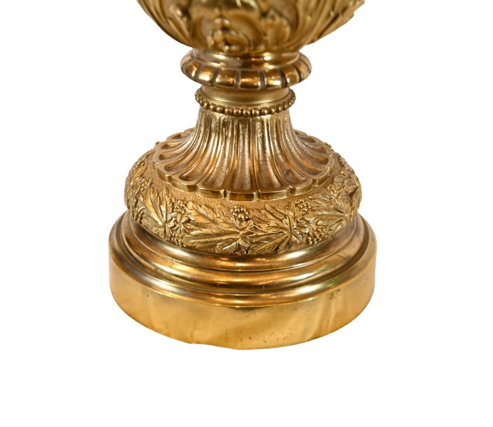 A pair of 19th-century French gilt bronze ewers featuring detailed Bacchus relief scenes, leaf motifs, and cherub-topped handles. View IV