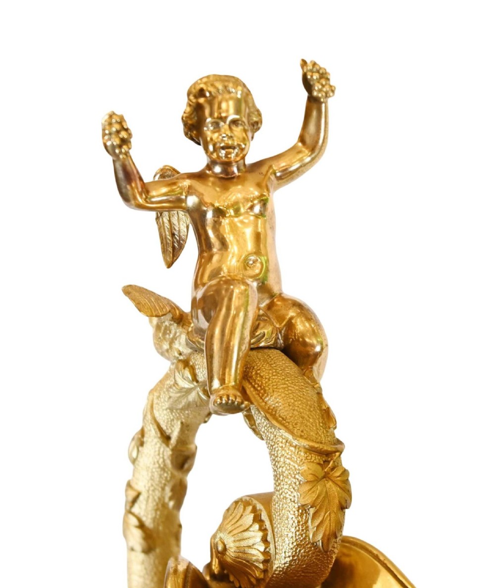 A pair of 19th-century French gilt bronze ewers featuring detailed Bacchus relief scenes, leaf motifs, and cherub-topped handles. View XIV