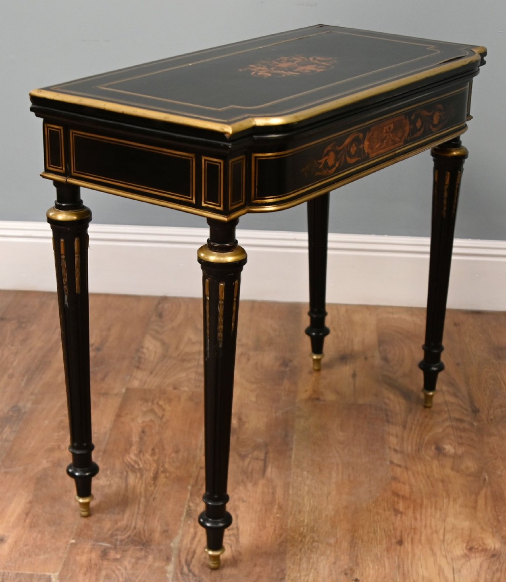 A late 19th-century French Napoleon III ebonised card table featuring floral marquetry inlay on the top and frieze with brass borders and tapered fluted legs. View VI