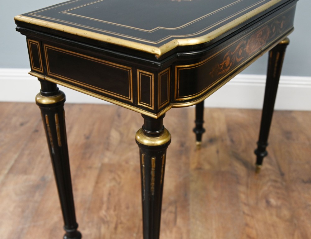 A late 19th-century French Napoleon III ebonised card table featuring floral marquetry inlay on the top and frieze with brass borders and tapered fluted legs. View VII