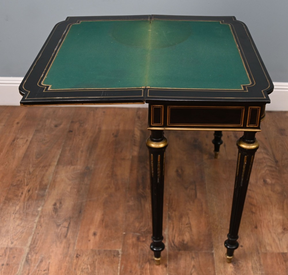 A late 19th-century French Napoleon III ebonised card table featuring floral marquetry inlay on the top and frieze with brass borders and tapered fluted legs. View IX