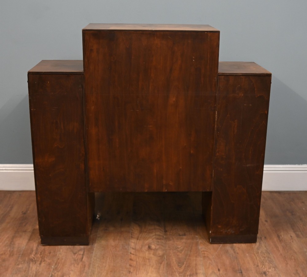 An Art Deco figured walnut display cabinet with a raised central open section containing two glass shelves, flanked by two side cupboards with arched veneer detailing. View VII