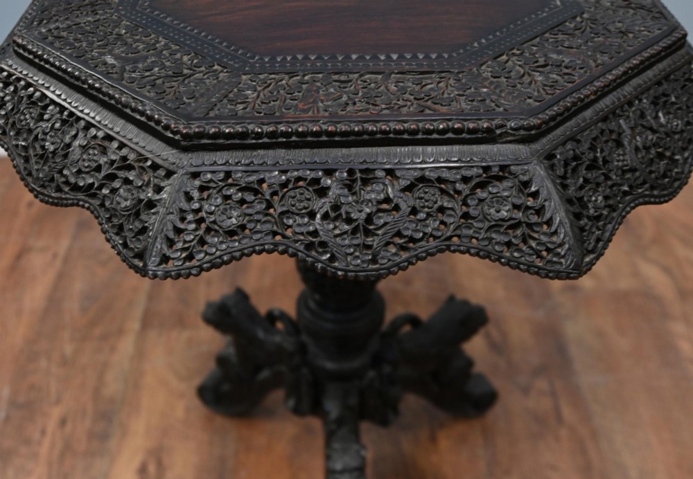 An antique octagonal dark hardwood side table featuring intricate pierced floral carvings around the apron and a central turned pedestal supported by three mythical carved beast legs. View VI